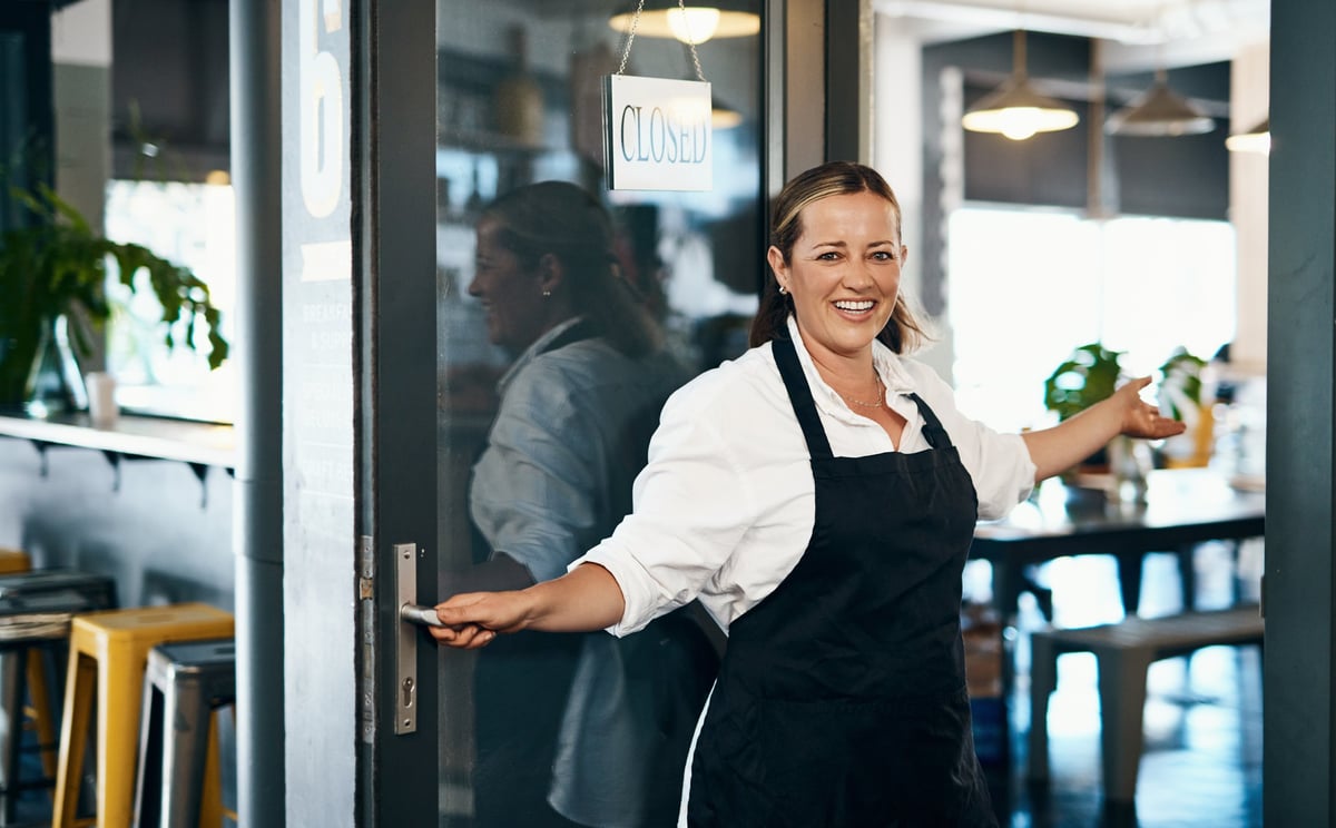Dueña de una cafetería abriendo la puerta de su negocio, lista para recibir clientes